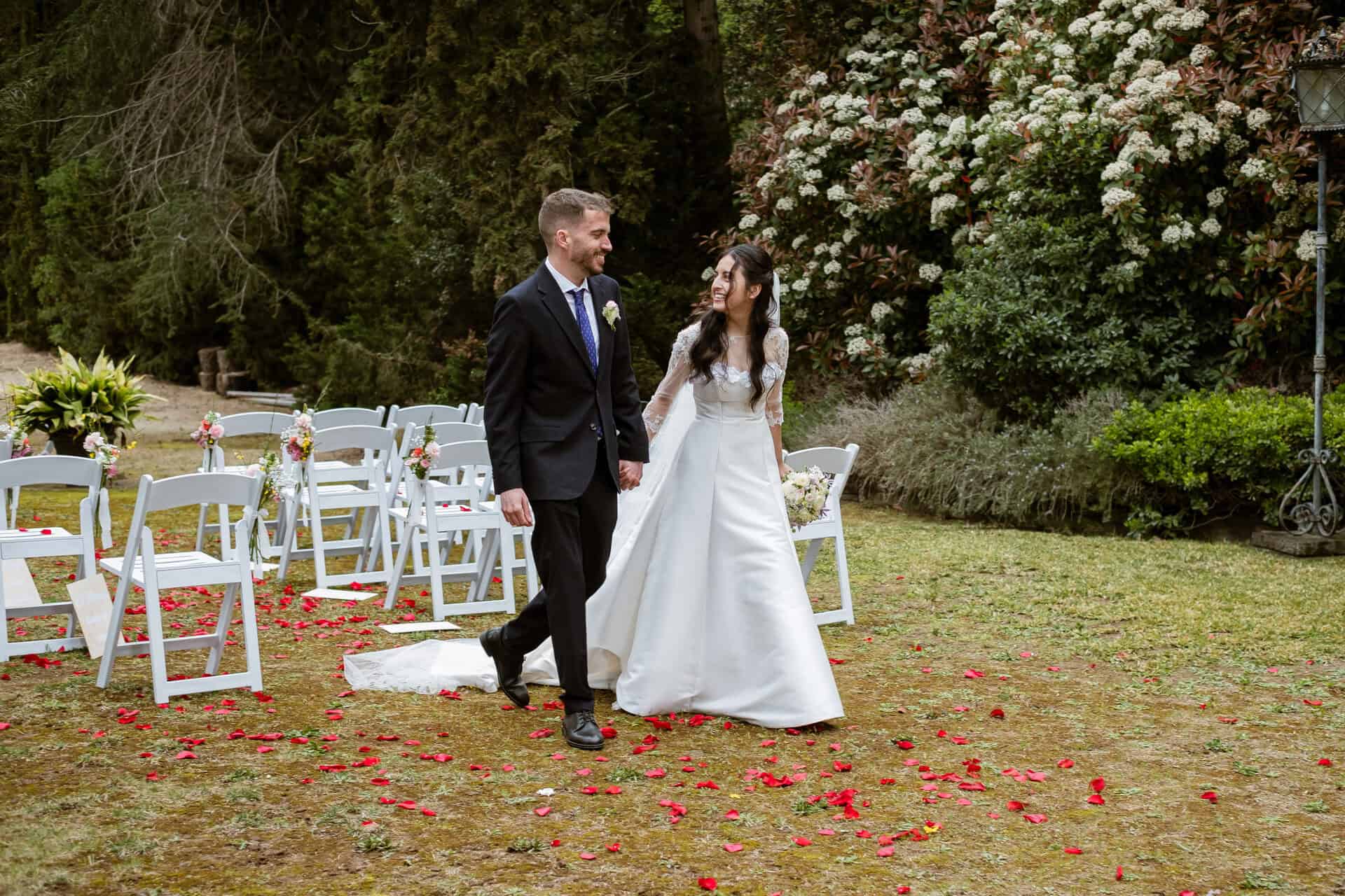 Novios en ceremonia de jardín con pétalos de flores